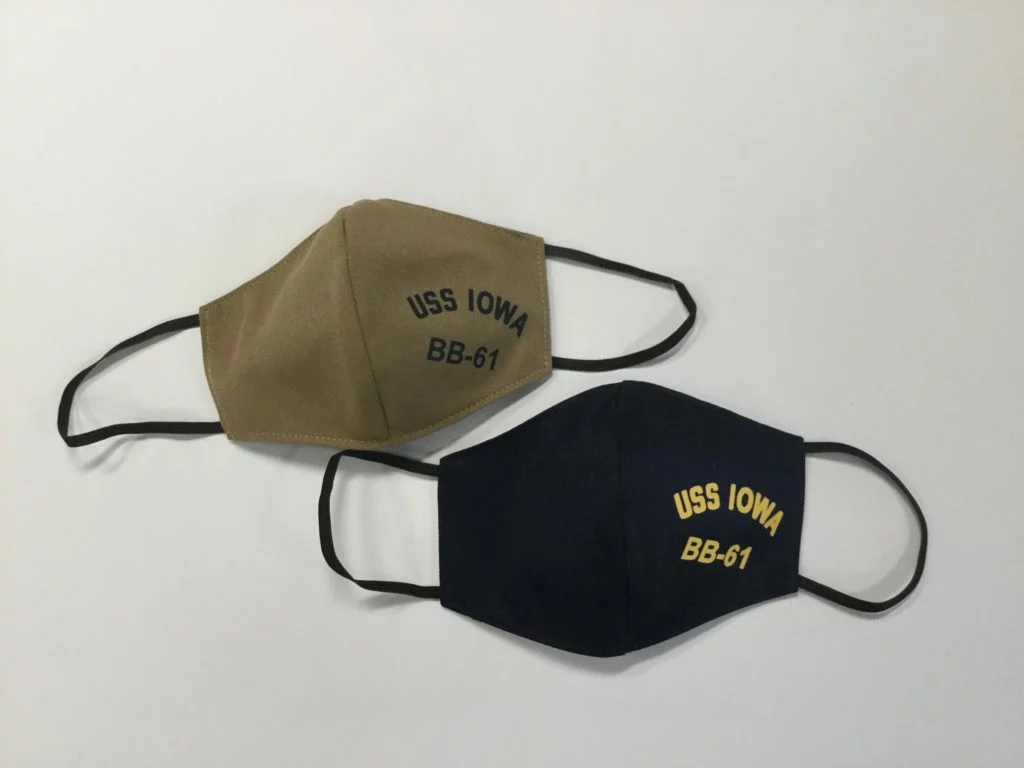 Two cloth face masks, one tan and one black, both with USS IOWA BB-61 printed on the front, are placed on a plain white surface. These masks pay tribute to the legendary Battleship USS Iowa, now a fascinating centerpiece at the Los Angeles museum. Two cloth face masks, one tan and one black, both with USS IOWA BB-61 printed on the front, are placed on a plain white surface. These masks pay tribute to the legendary Battleship USS Iowa, now a fascinating centerpiece at the Los Angeles museum.