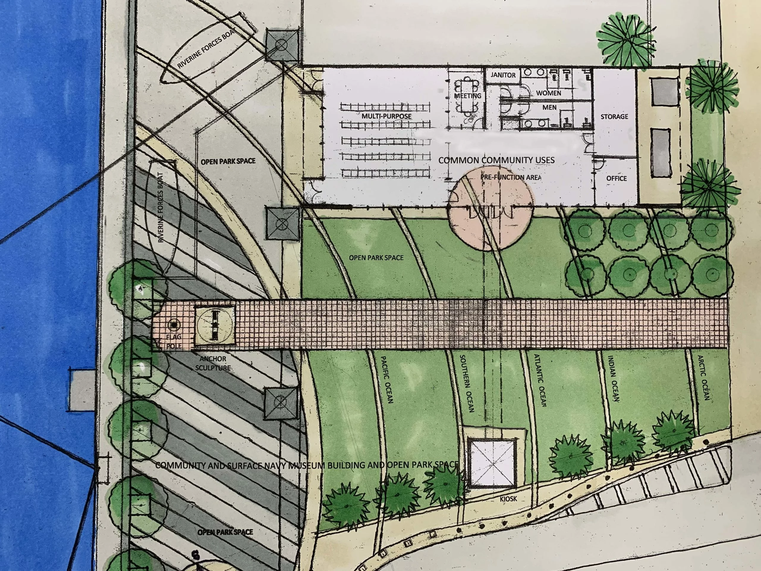 Architectural site plan showing a community building, open park spaces, walkways, trees, parking, and access to a waterfront. The layout is labeled with functional areas and pathways for visitors, with dedicated announcements areas strategically placed throughout the site for sharing community news and events.