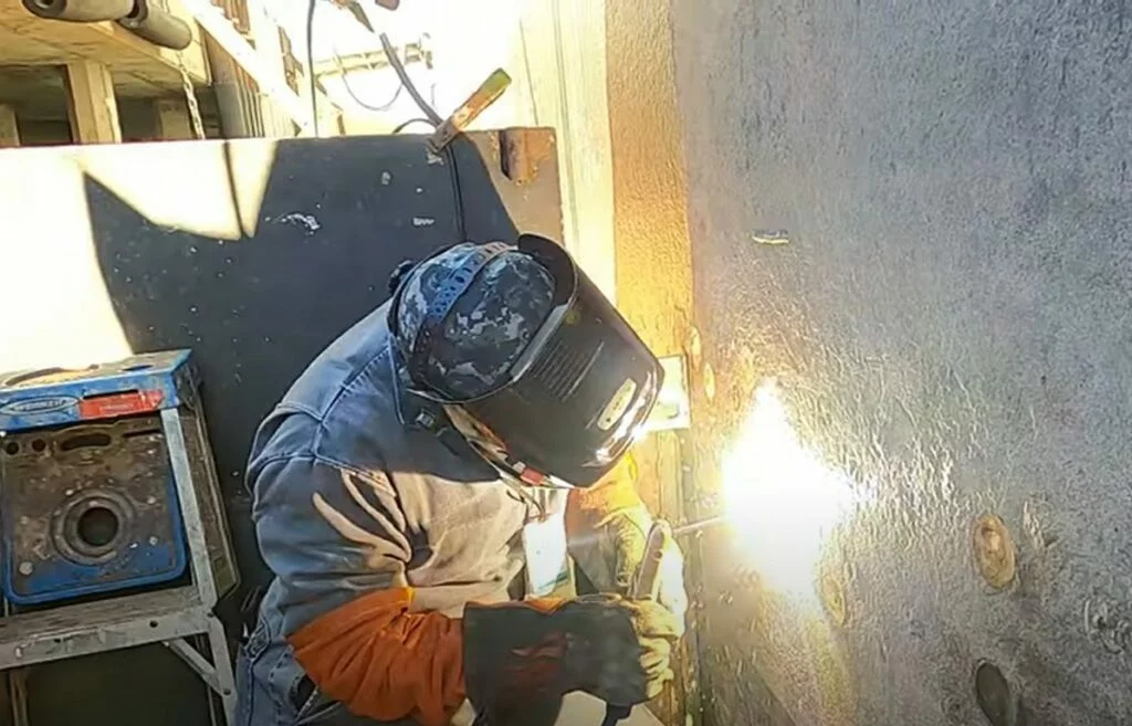 A person wearing protective gear and a welding helmet uses a welding torch on a metal surface, producing bright sparks in an industrial setting—highlighting the dedication and hands-on expertise often discussed in our latest CEO Update.